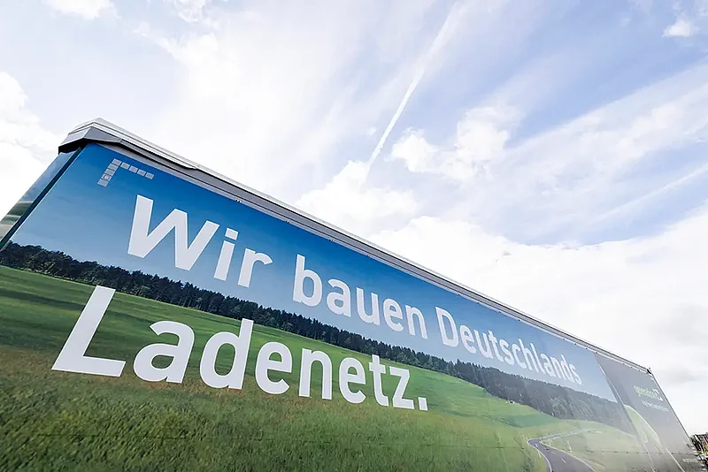 generation E Ladepark Kiel 6 Detailansicht eines Lkw-Aufliegers mit der Aufschrift „Wir bauen Deutschlands Ladenetz“.