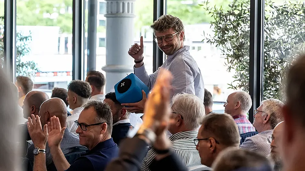 Stehender Mann im Publikum zeigt grinsende einen Daumen nach oben 